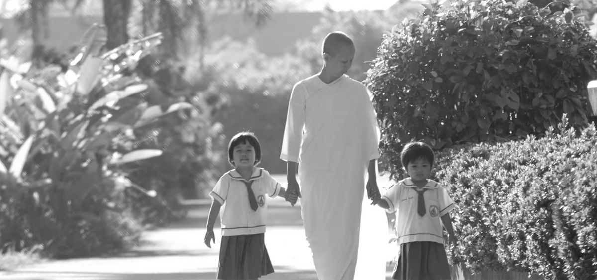 a woman in a white robe walking with two children