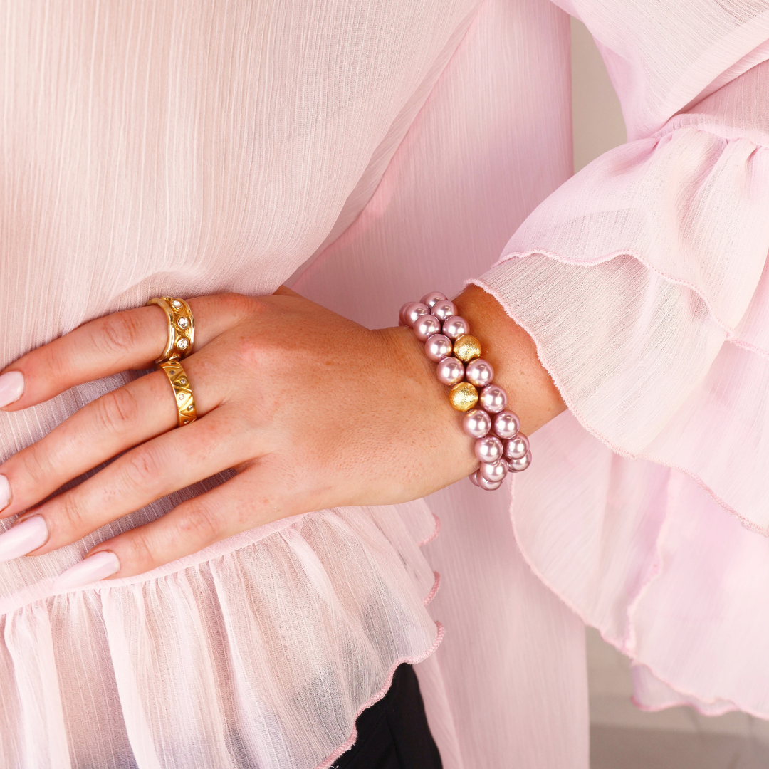 a woman wearing a pink blouse and bracelets