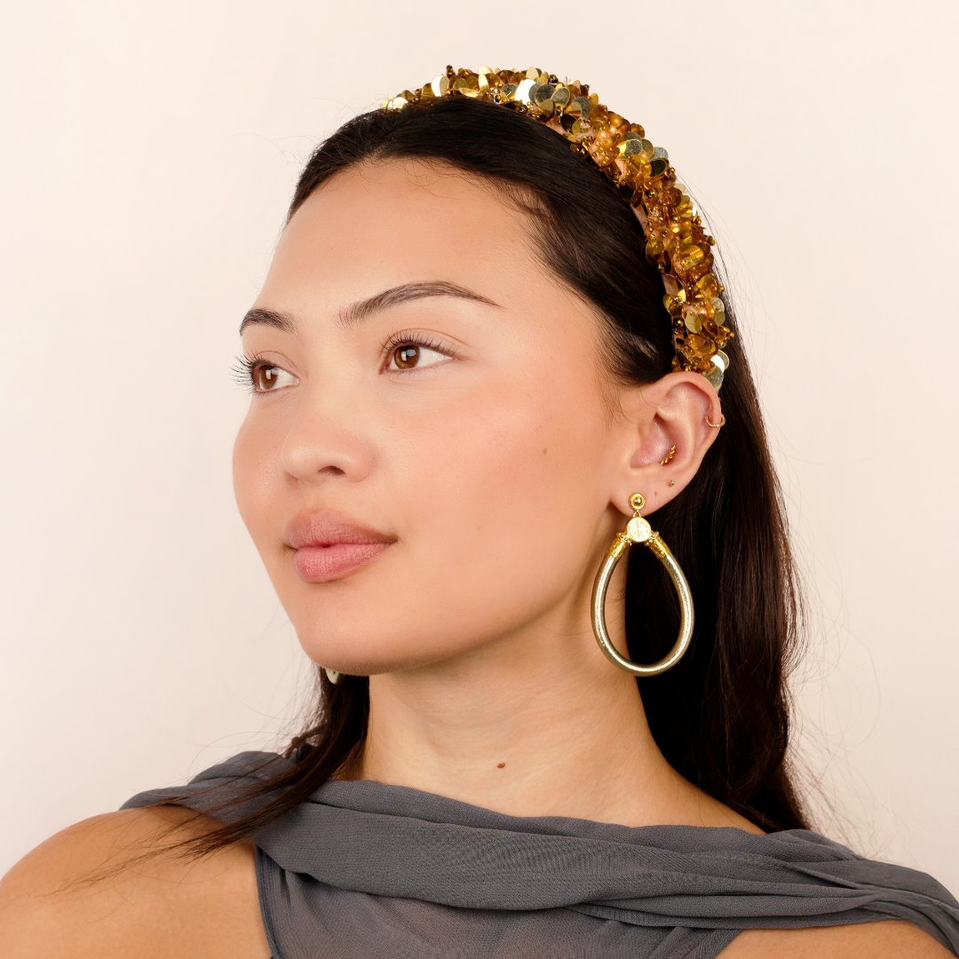 a woman wearing a gold headband and earrings