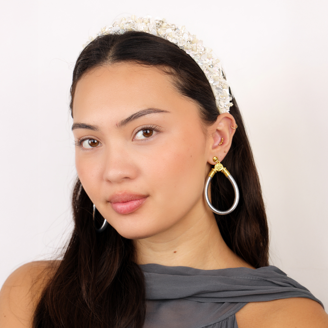 a woman with a white headband and earrings