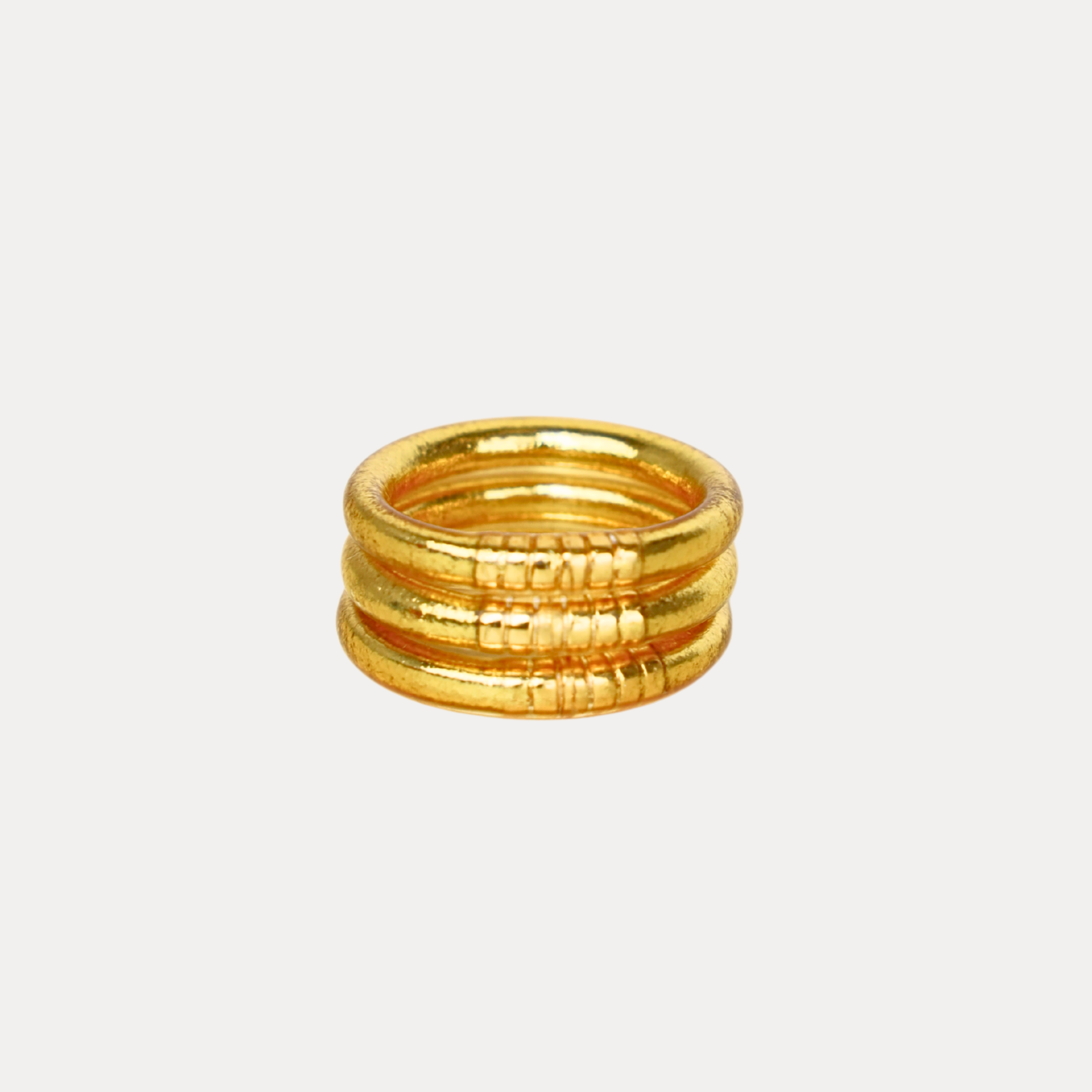 Stack of gold rings on a light gray background