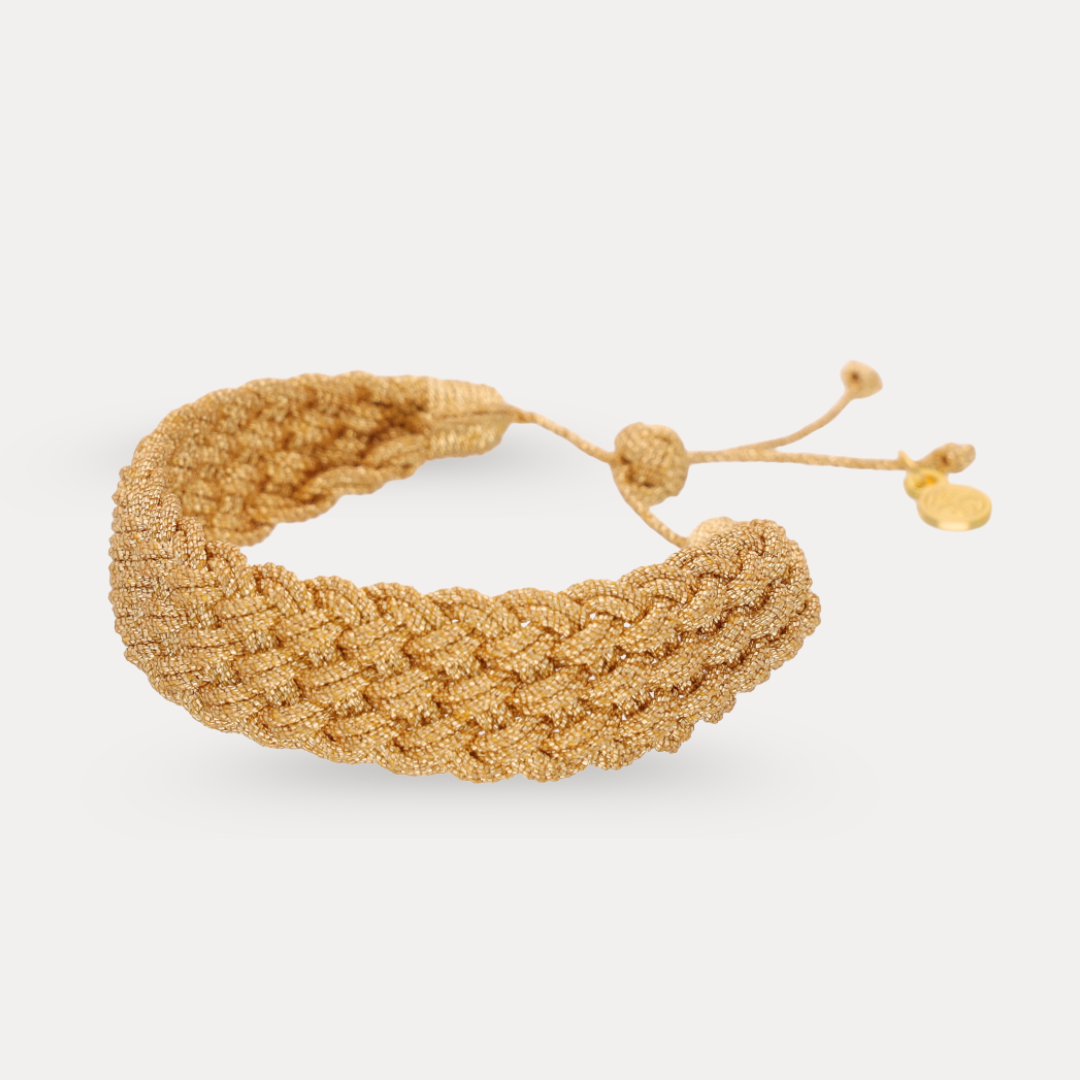 a gold woven bracelet with a string