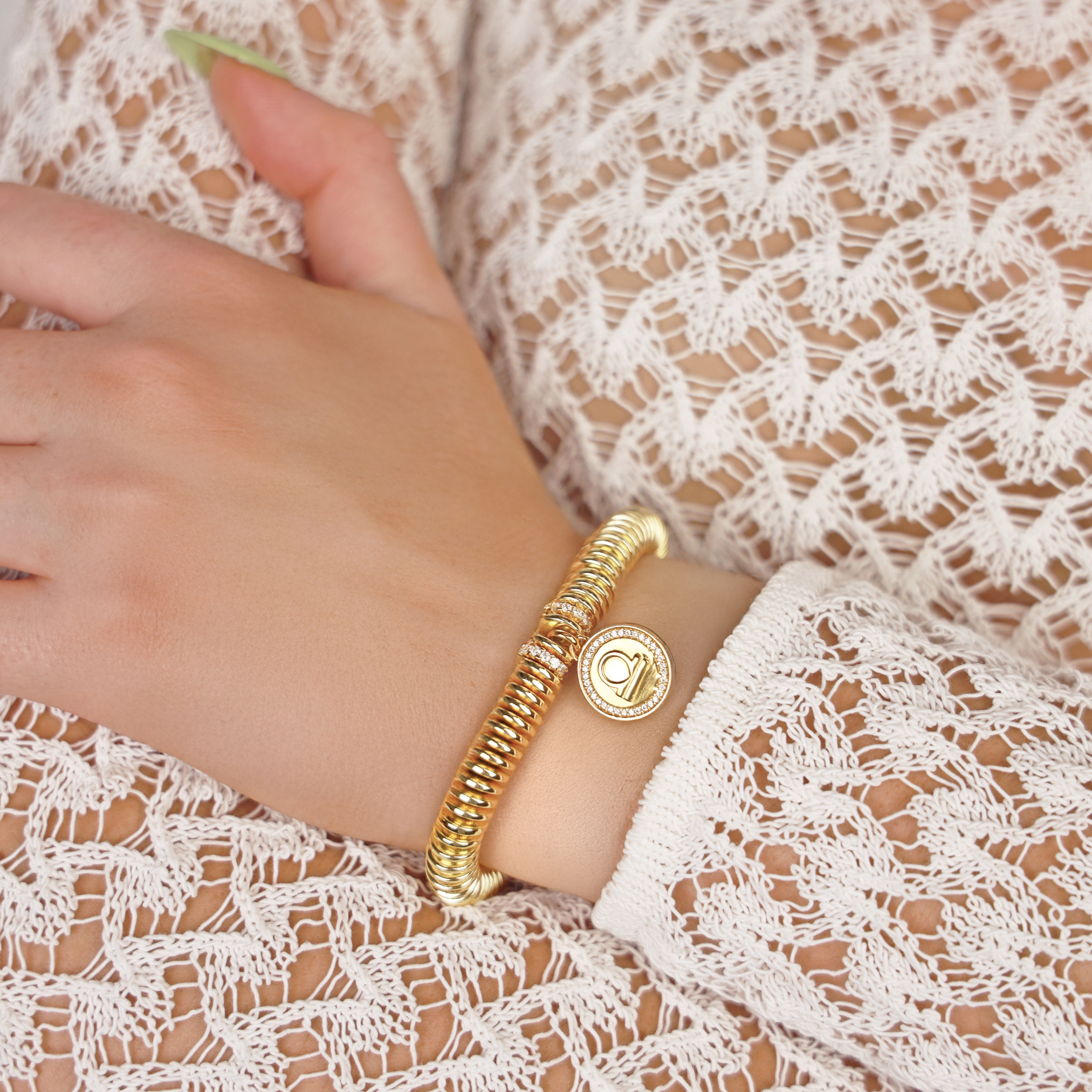 Gold bracelet on a wrist with a lace garment in the background