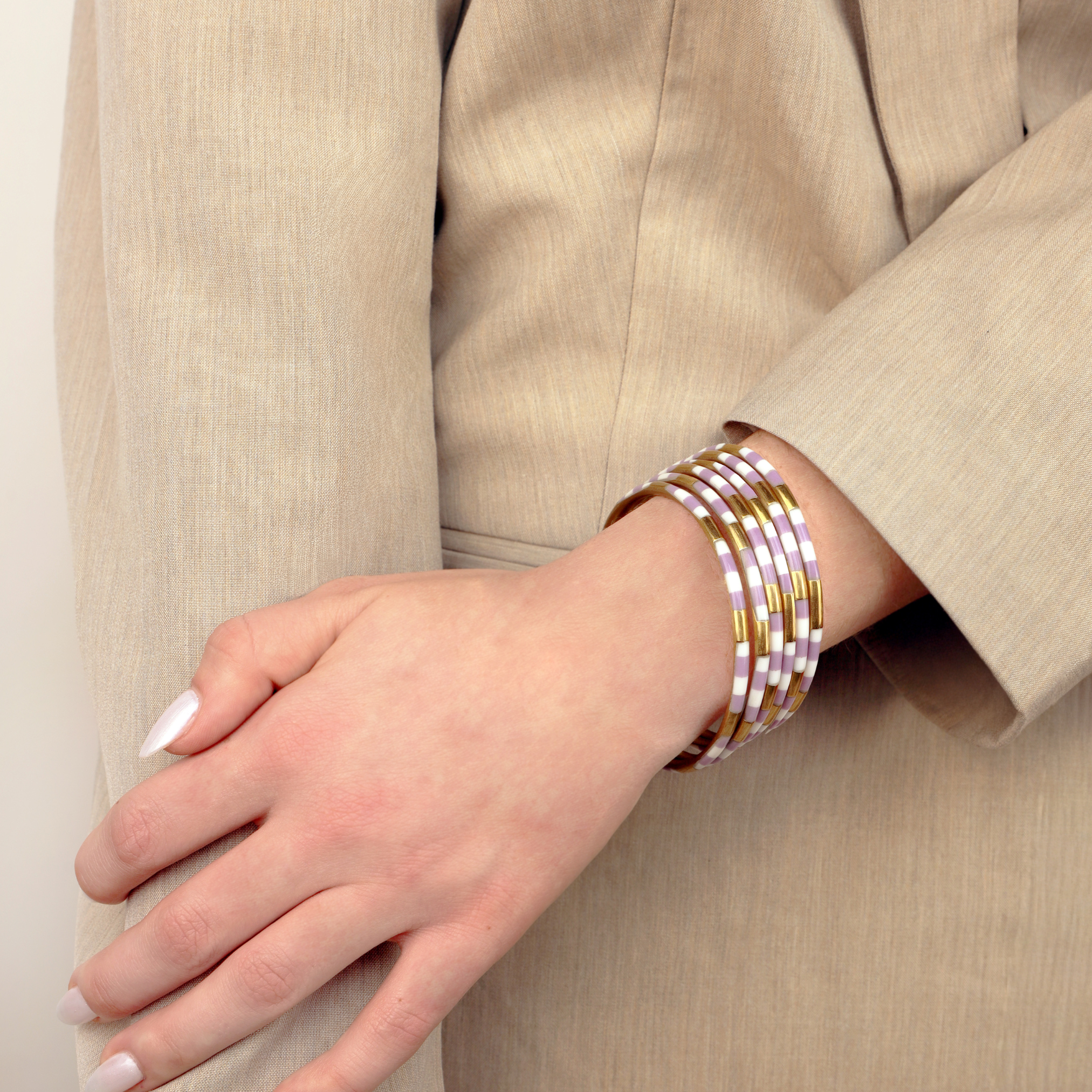 a woman wearing a beige jacket and bracelets