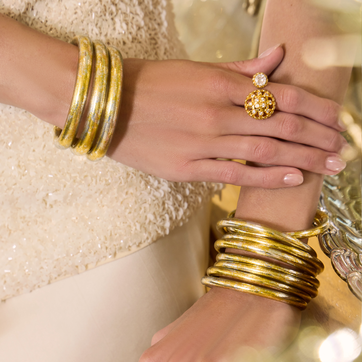 BuDhaGirl bangle bracelets for women in warm gold and cool silver tones stacked on both wrists with a sculptural ring and elegant neutral styling