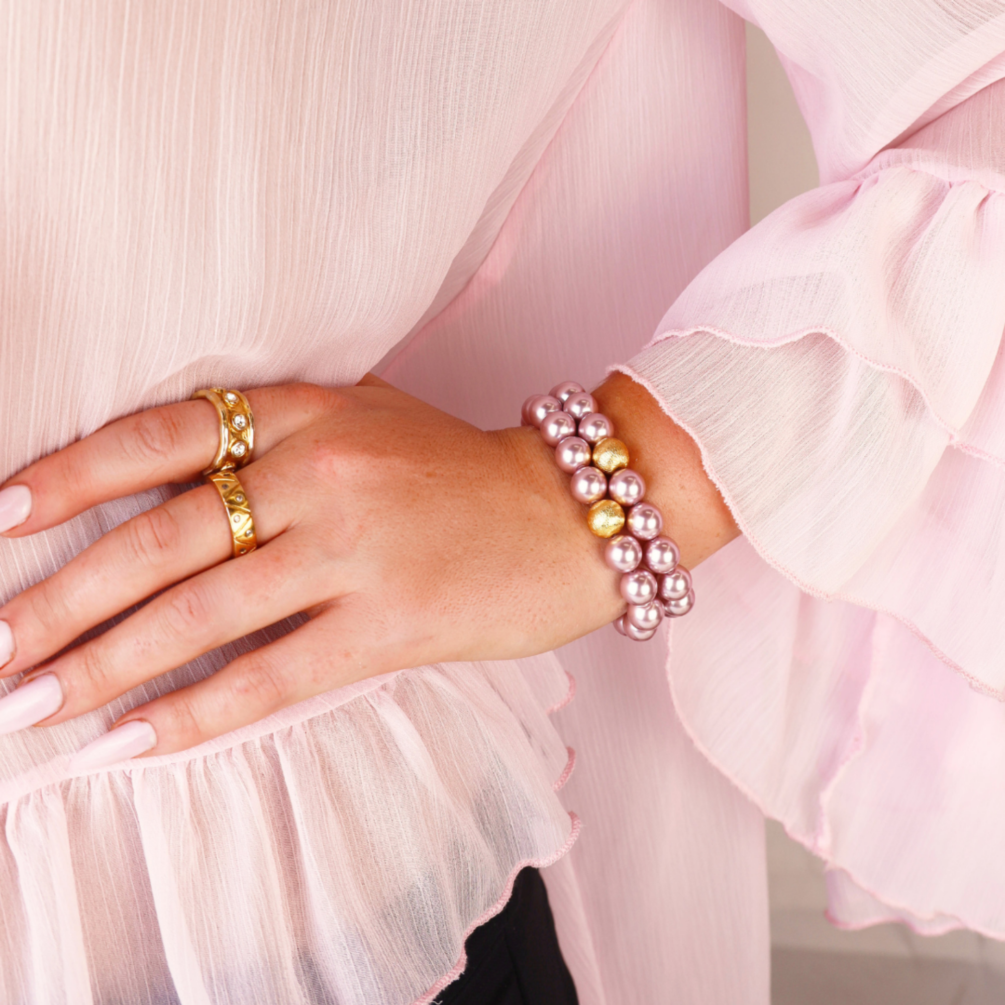 a woman wearing pink and gold jewelry
