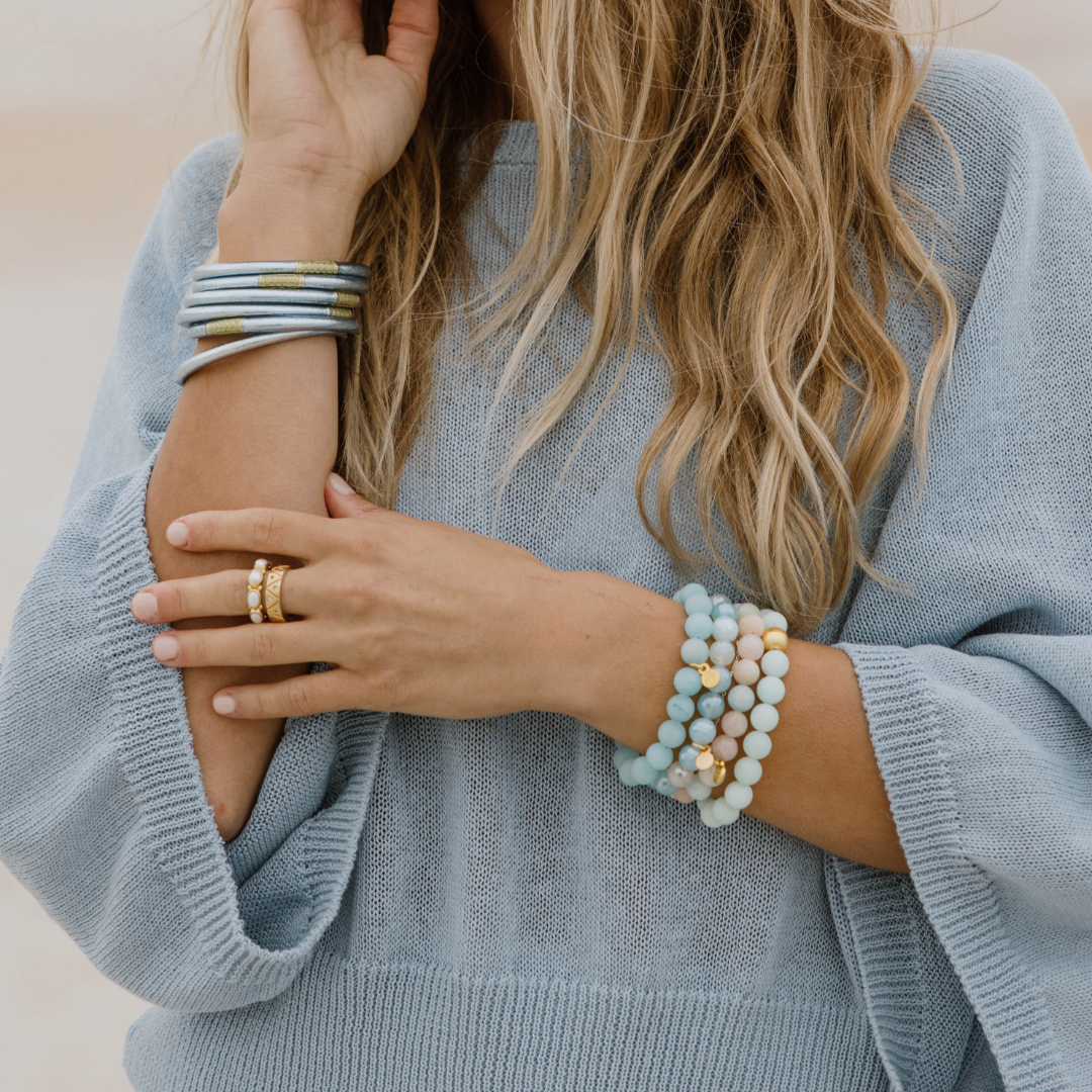 a woman wearing a blue sweater and bracelets