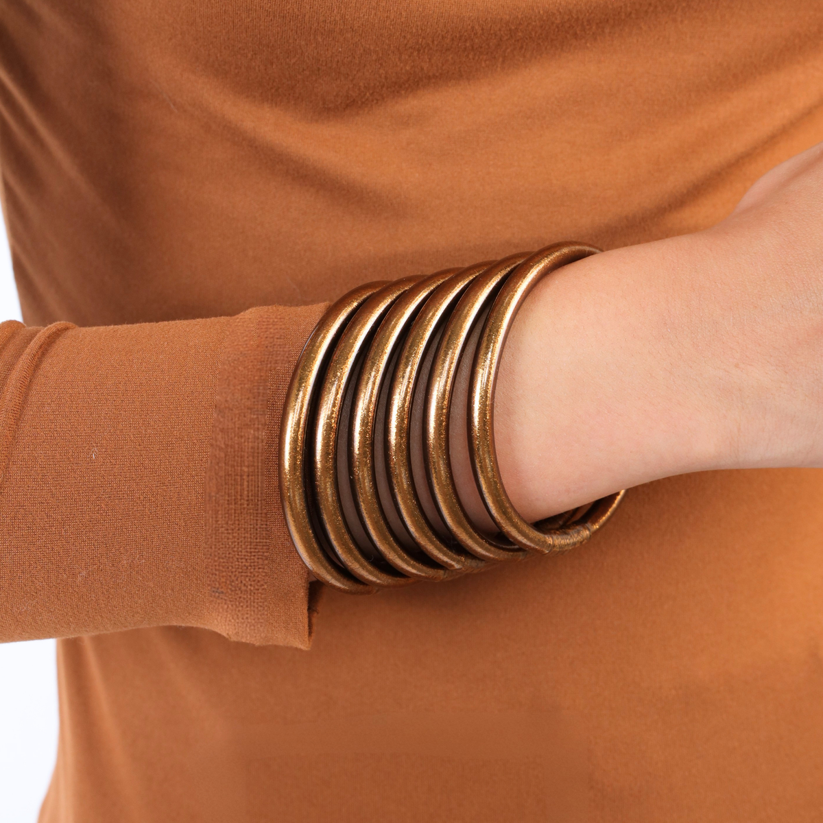 a person wearing a brown shirt and bracelets