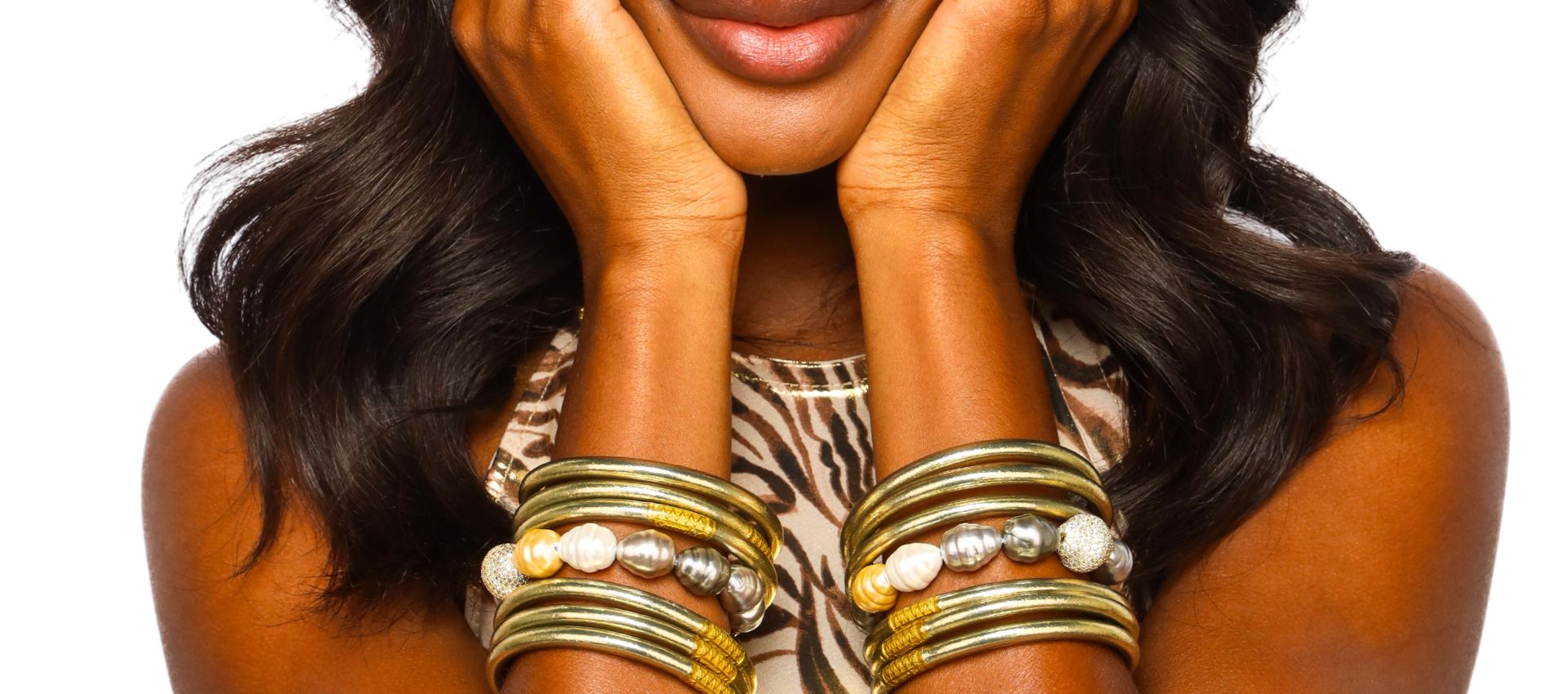 Woman in Animal Print Dress Wearing Etoile Light Gold All Weather Bangle Bracelets and Isabel Baroque Pearl Bracelets | BuDhaGirl