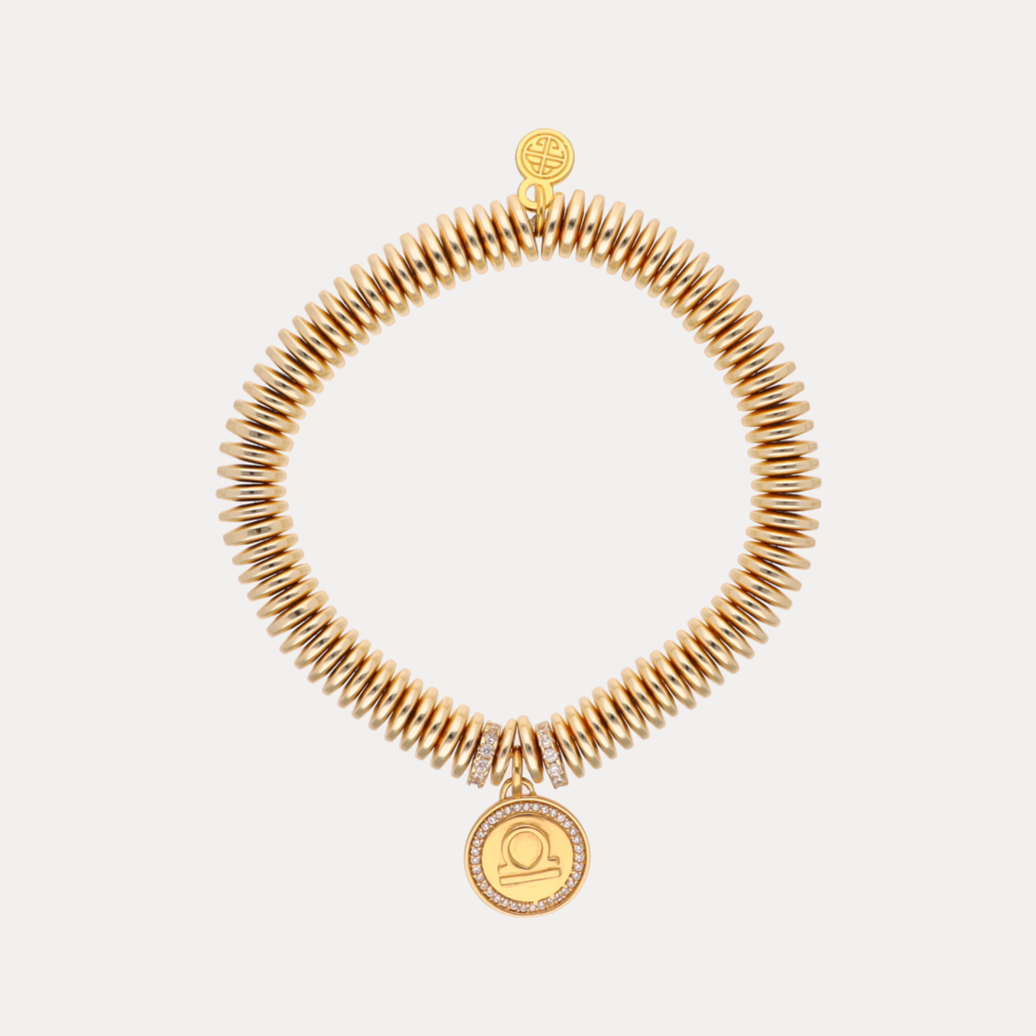 Gold bracelet with a circular charm on a light gray background