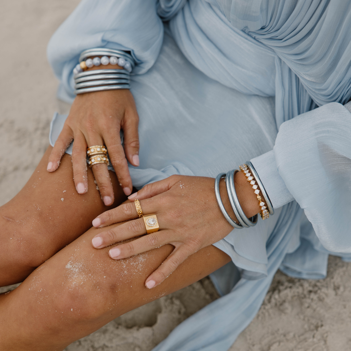 a person wearing jewelry and sitting on the sand