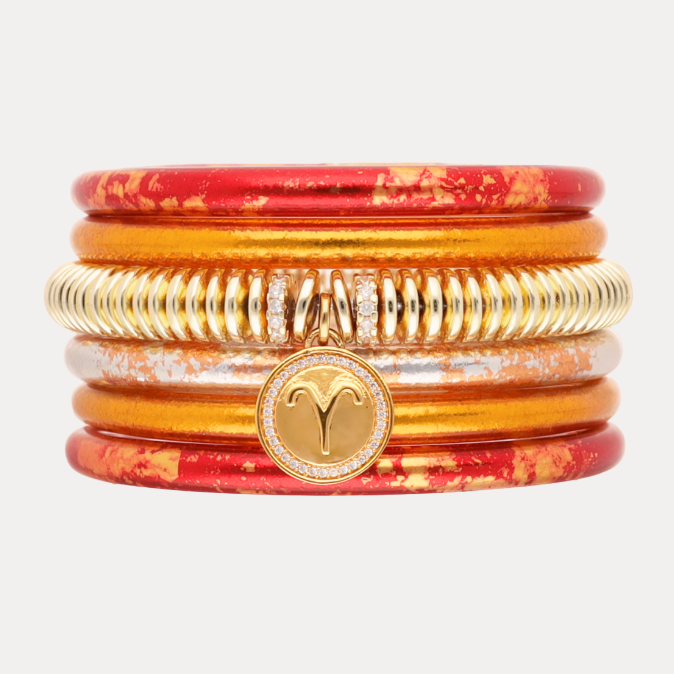 Stack of red and gold bangles with a colorful sky background